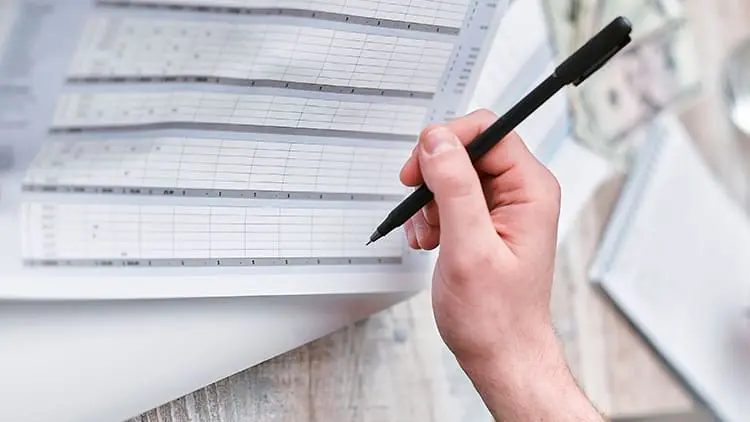 Mano con bolígrafo revisando un desglose de costes para el envío de presupuestos personalizados de limpieza con Klin.