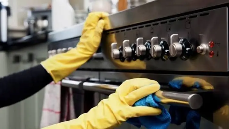 Personal de limpieza con guantes amarillos realizando la desinfección profunda de una cocina de acero inoxidable con Klinn.