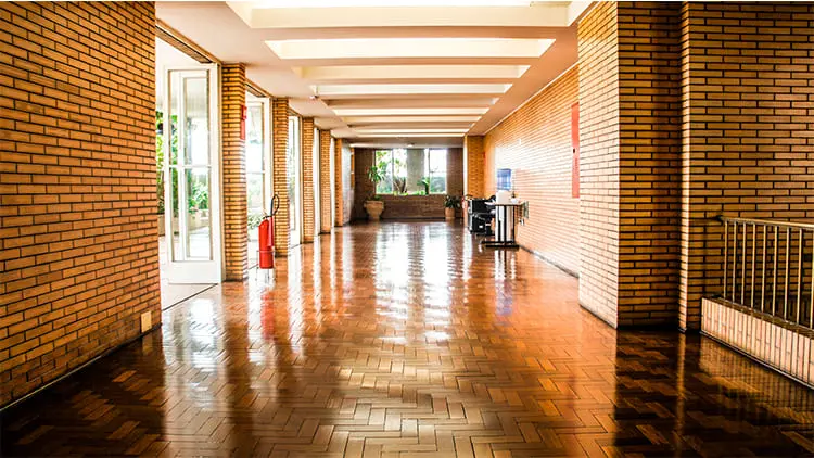 Pasillo amplio de un edificio residencial con suelo de madera pulido y brillante tras el servicio de limpieza de comunidades de Klinn.