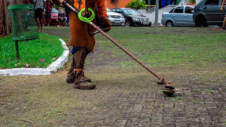 Operario realizando el mantenimiento de áreas verdes y limpieza de adoquines con una desbrozadora para Klinn.