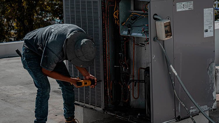 Técnico especializado realizando la reparación y mantenimiento de una unidad de aire acondicionado exterior con Klinn.
