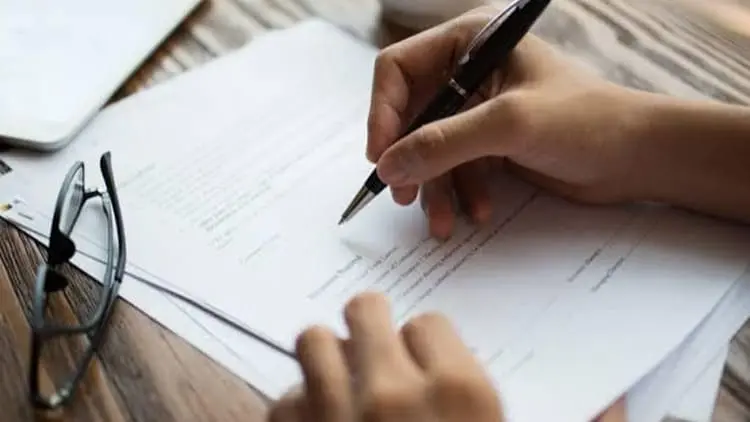 Persona firmando un contrato legal impreso que representa las garantías y políticas de servicio de Klinn.