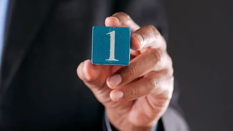 Primer plano de una mano sosteniendo un cubo azul con el número uno, representando el servicio de limpieza número 1 de Klinn.