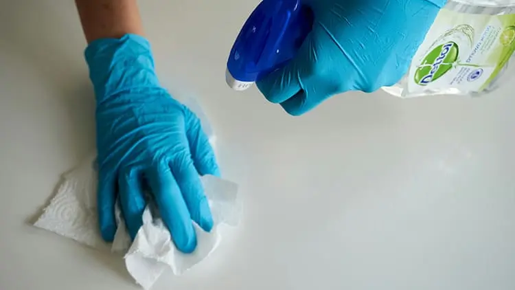 Personal de limpieza profesional con guantes y desinfectante limpiando en profundidad una superficie.